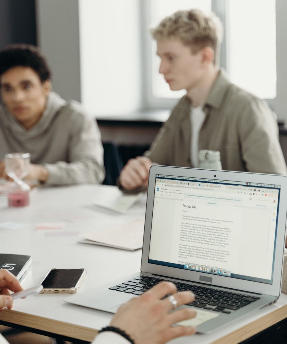 Des apprenants autour d'une table, l'un d'eux suit un module sur son ordinateur portable